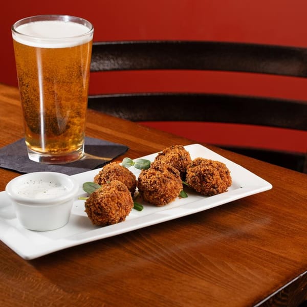 Crispy Harold Dean Smoked Goods BBQ hushpuppies with dipping sauce and a pint of beer.