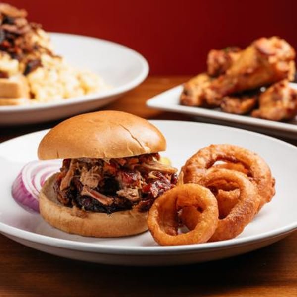 Harold Dean Smoked Goods pulled pork sandwich with onion rings, red onion, and other BBQ dishes.